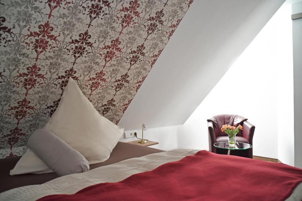 a bedroom with a bed with a red blanket and a chair at Hotel Zur Eisenbahn in Renningen