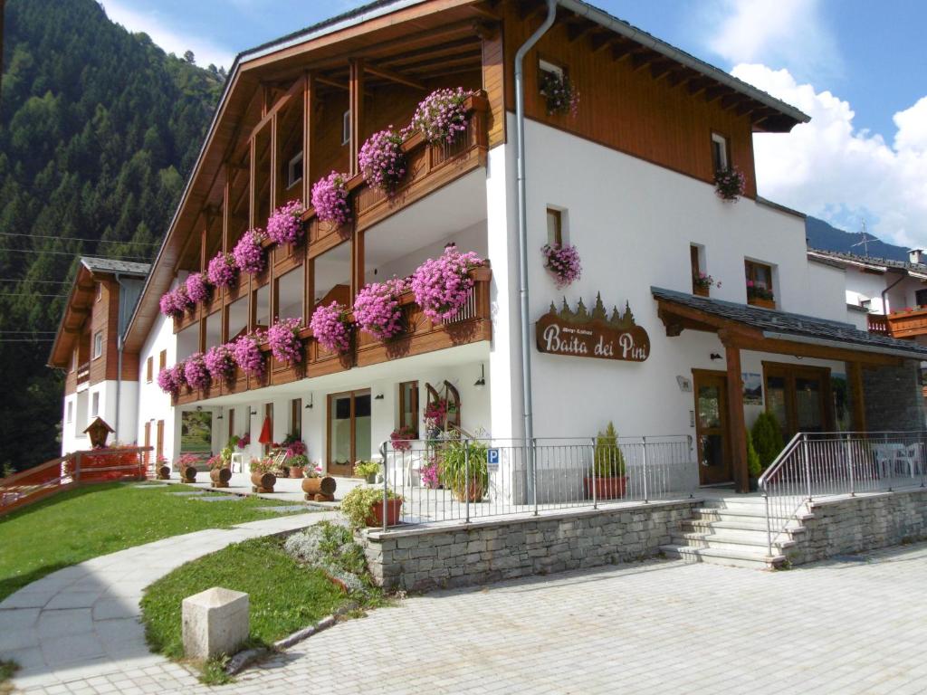 un bâtiment avec des fleurs sur son côté dans l'établissement Baita dei Pini, à Campodolcino