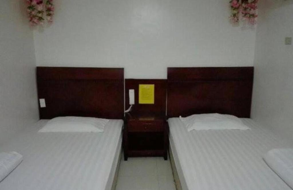 twee bedden in een kleine kamer met twee bedden sidx sidx sidx bij Asia Novo Boutique Hotel - Kalibo in Kalibo