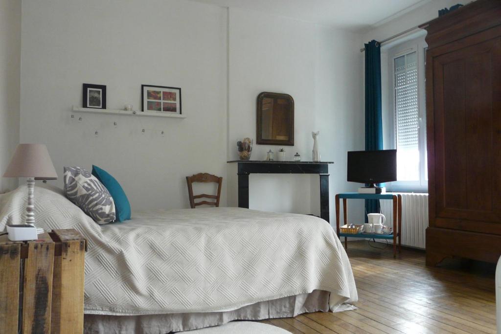 een slaapkamer met een bed en een open haard bij La Pie Grièche in Coucy