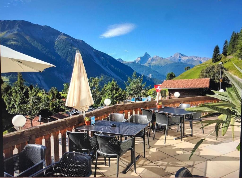 eine Terrasse mit Tischen und Stühlen mit Bergen im Hintergrund in der Unterkunft Hotel Sonnenhalde in Wiesen