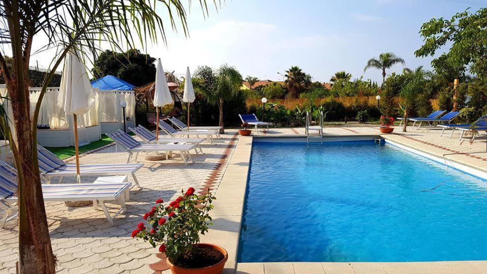a swimming pool with lounge chairs and umbrellas at Villa Conti in Giardini Naxos
