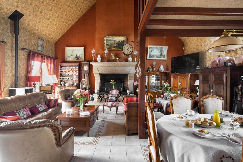 ein Wohnzimmer mit Tischen, Stühlen und einem Kamin in der Unterkunft Chez Marie et Jean François in Dol-de-Bretagne