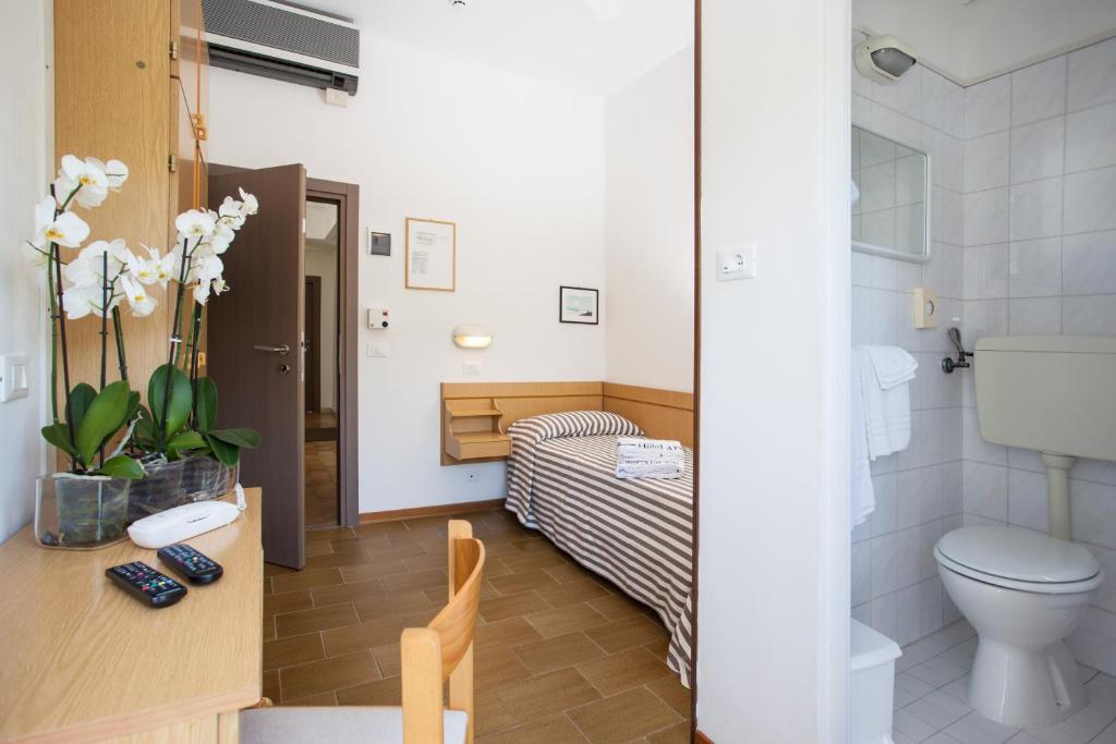 a bathroom with a toilet and a bed in a room at Hotel Adler in Gabicce Mare