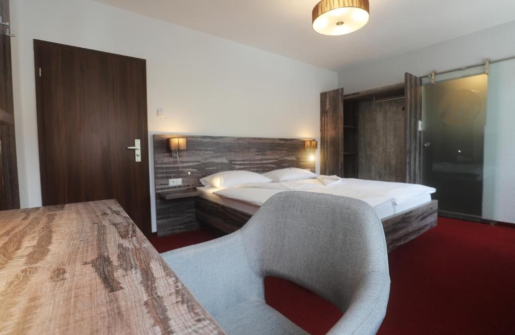 ein Hotelzimmer mit einem Bett und einem Stuhl in der Unterkunft stadthotel miya in Bad Mergentheim