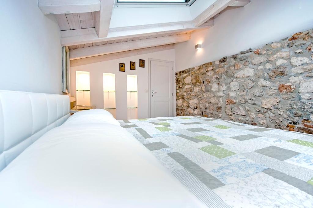 1 dormitorio con cama y pared de piedra en Apartment and Studio CA’ 3 VIE, en Rovinj