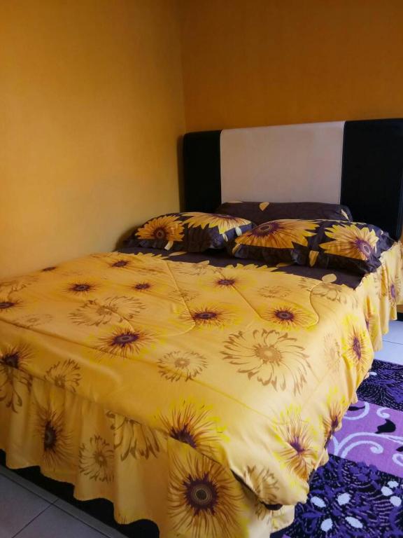un letto con una coperta gialla con girasoli sopra di Midi Homestay a Batu
