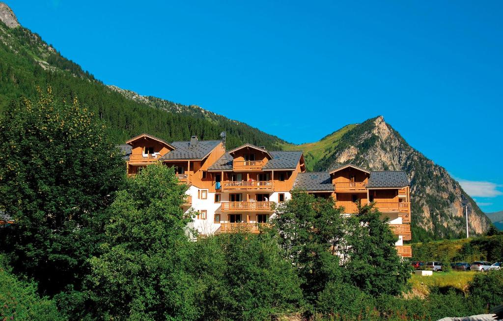 a large hotel in the mountains with trees at Résidence Goélia Le Blanchot in Pralognan-la-Vanoise