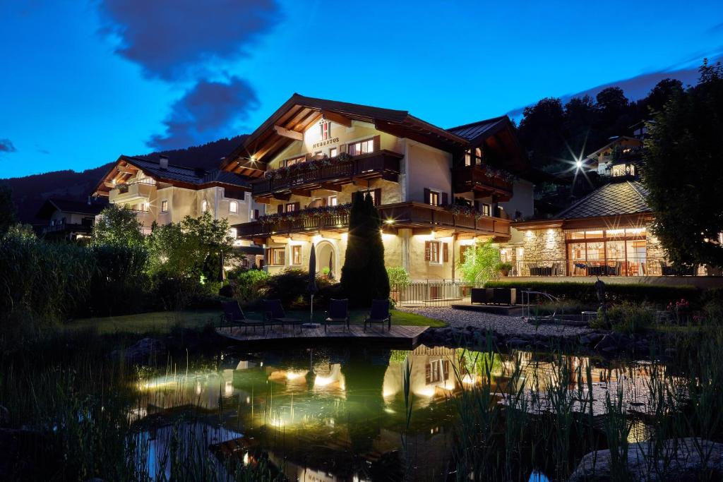 ein Haus mit einem Teich davor in der Nacht in der Unterkunft Hotel Hubertus in Brixen im Thale