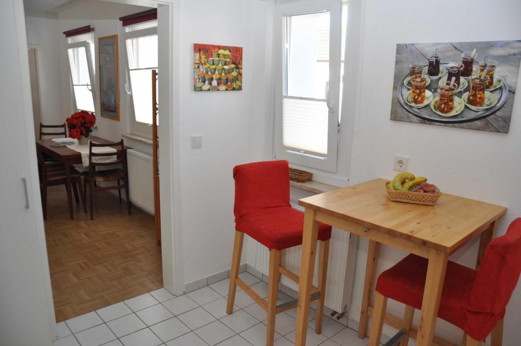 kuchnia i jadalnia ze stołem i czerwonymi krzesłami w obiekcie Appartment in Troisdorf-Sieglar w mieście Troisdorf