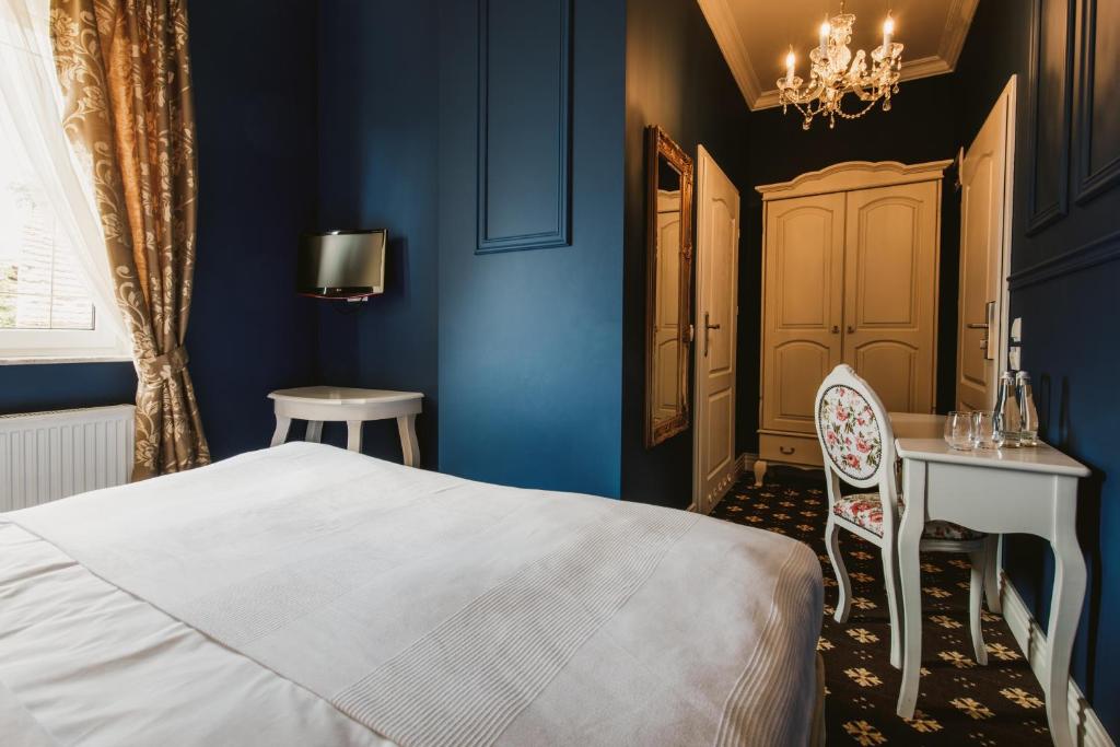 een slaapkamer met blauwe muren en een bed en een bureau bij Via Villa in Nowe Kramsko