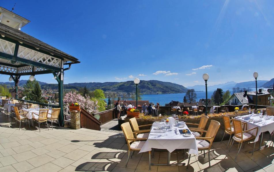 un patio con mesas y sillas y vistas al agua en Hotel Restaurant Häupl, en Seewalchen