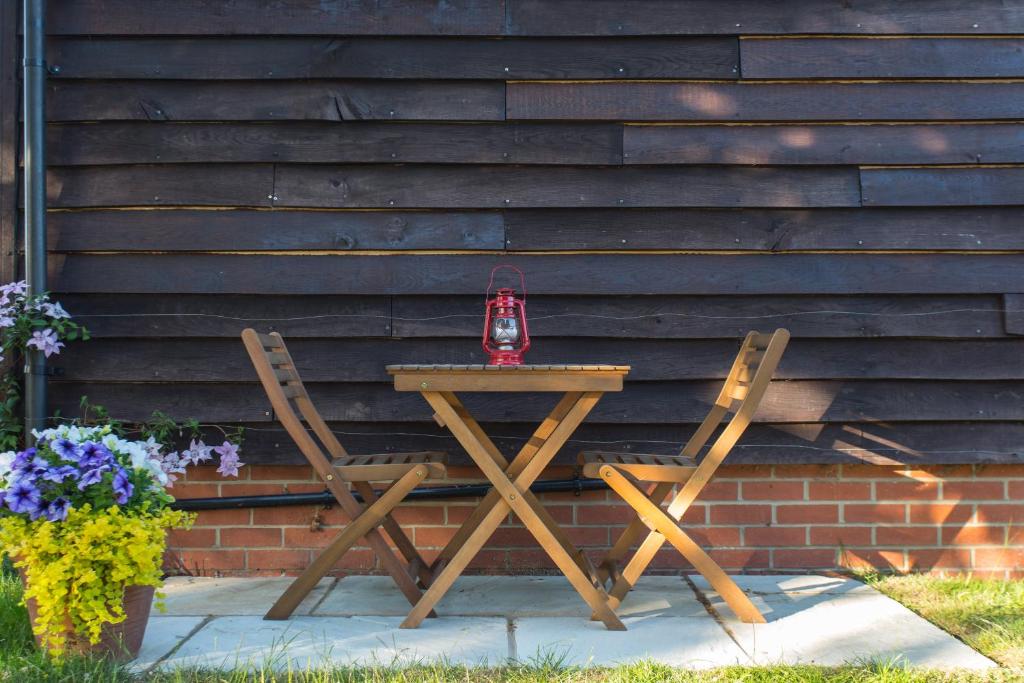 a wooden table and two chairs with a red candle on it at Linden House in West Wittering