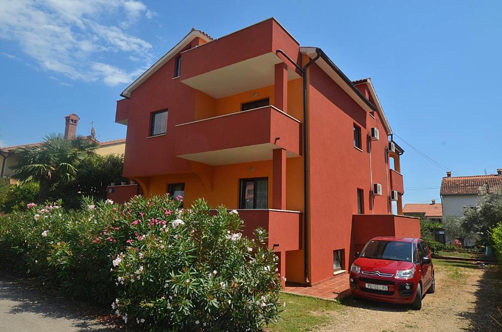 une voiture rouge garée devant un bâtiment rouge dans l'établissement Casa Sol Maris, à Novigrad