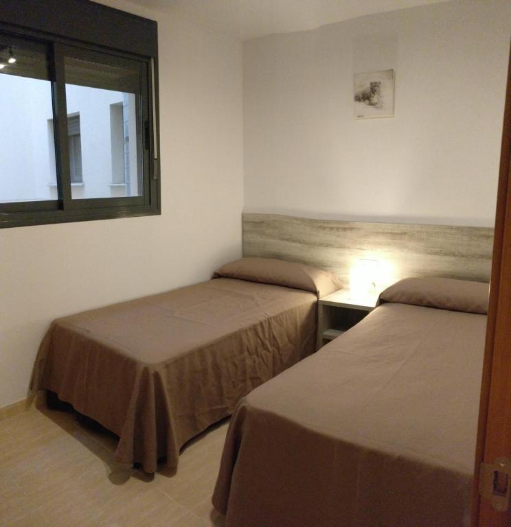 a room with two beds and a window at Apartamentos Prado in Peniscola