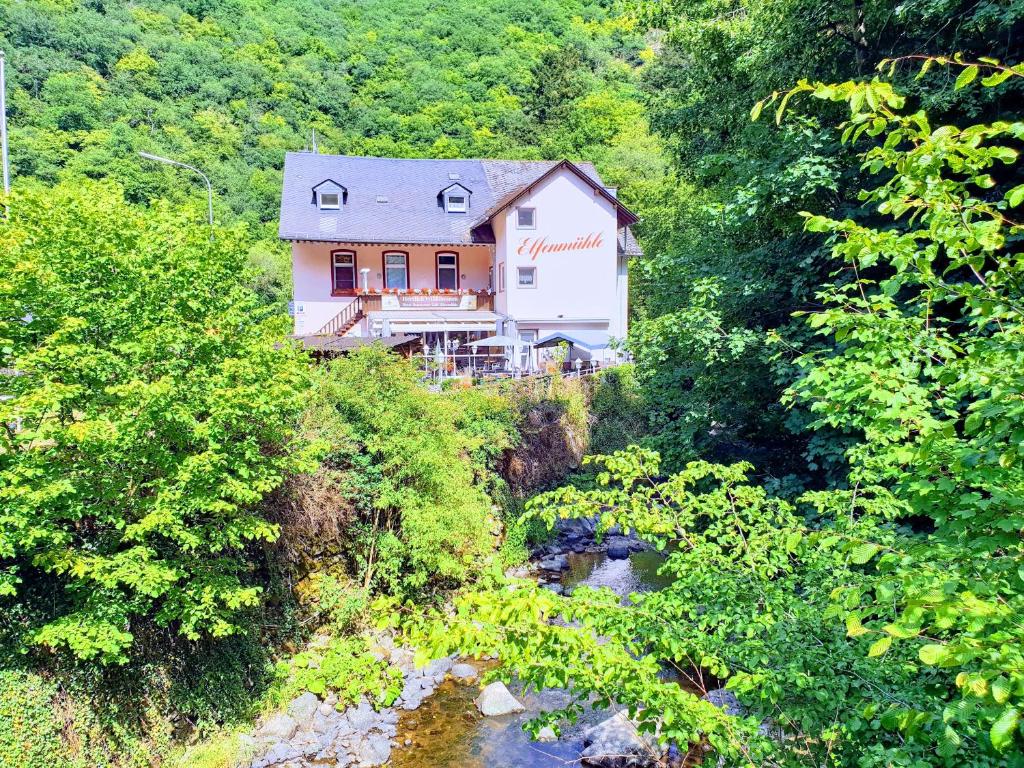 ein Haus auf einem Hügel neben einem Fluss in der Unterkunft Hotel Elfenmühle in Bad Bertrich