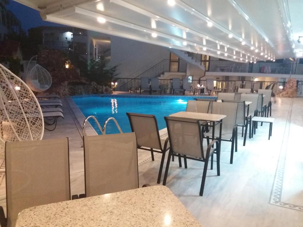 un restaurante con piscina, mesas y sillas en Pegasus Hotel, en Chaniotis