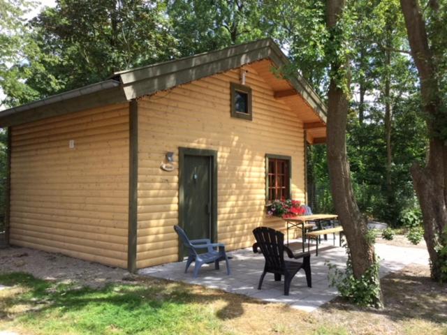 um pequeno barracão com cadeiras e uma mesa em frente em Hollands Oostenrijks huisje em Wieringerwerf