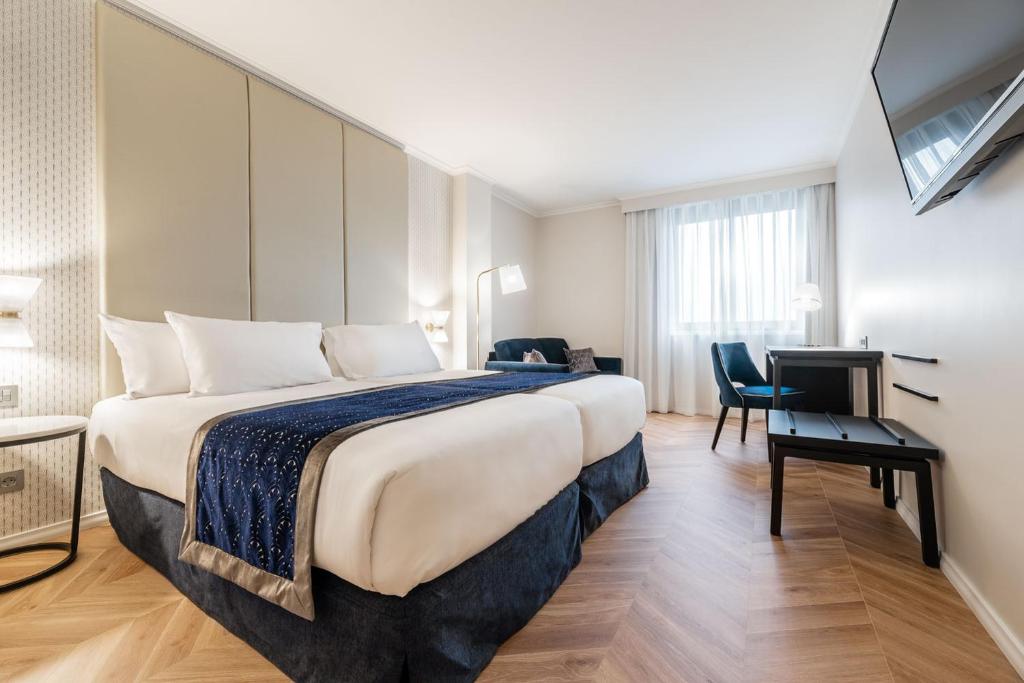 Una habitación de hotel con una cama grande y un escritorio. en Eurostars Gran Hotel Lugo, en Lugo