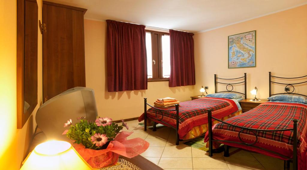 un dormitorio con 2 camas y una mesa con un jarrón de flores en BorgoAntico Affittacamere, en Soave