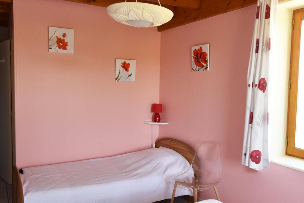 Un dormitorio con una pared rosa y una cama en La Bardelière en Corbelin