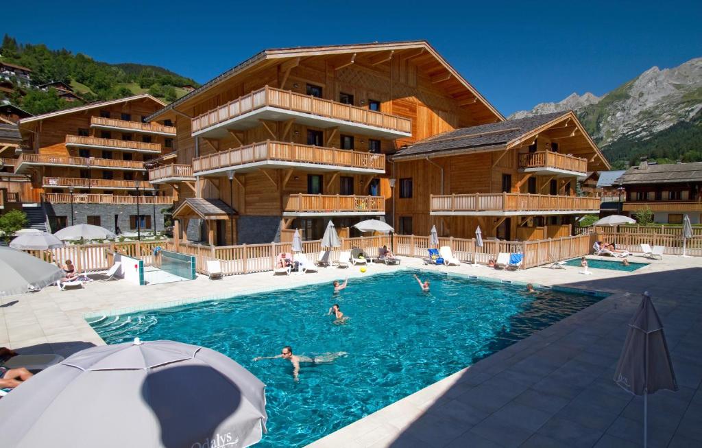 a pool in front of a hotel with people in it at Hôtel et Spa Le Chamois by Odalys in La Clusaz