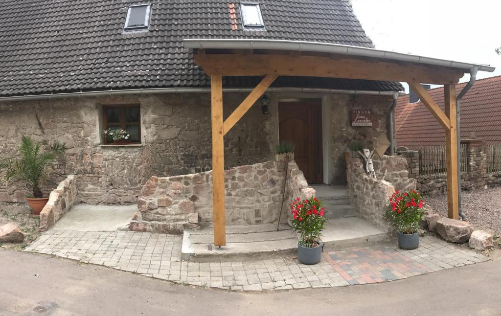 una casa de piedra con un pabellón con flores delante en Pension Casa Luciko, en Brachwitz