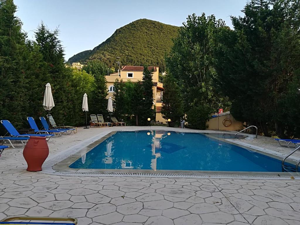 a swimming pool with chairs and a mountain in the background at Villa Litsa in Ermones