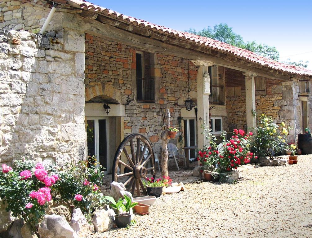 a stone house with a wheel and flowers in front of it at Domaine Audubert in Saint-Antonin