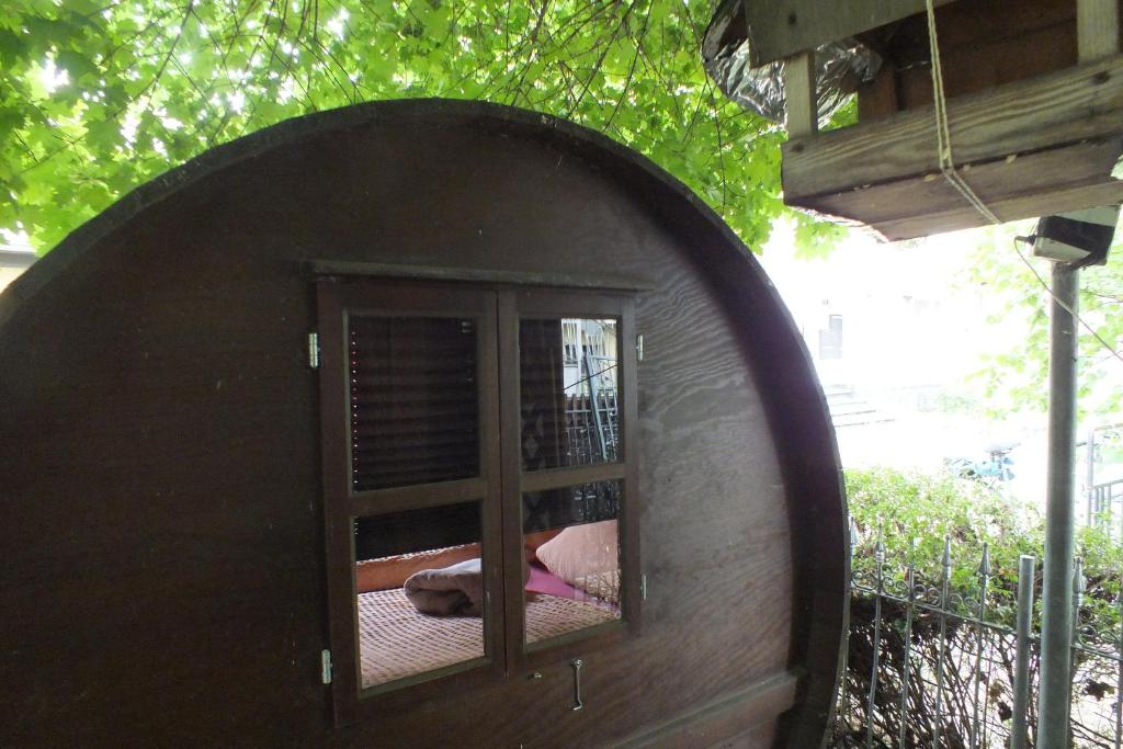 a dog laying in a window in a dog house at Für Alleinreisende-1 Person- Single Room- Rustikales freistehendes Mini Holzfass zum Schlafen, mit angrenzendem Badezimmer! in Leverkusen