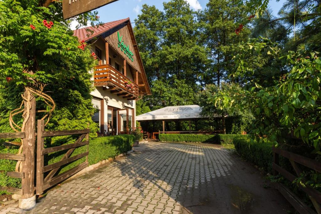 a building with a fence next to a walkway at Pensiunea Restaurant Vándor in Cîmpu Cetăţii