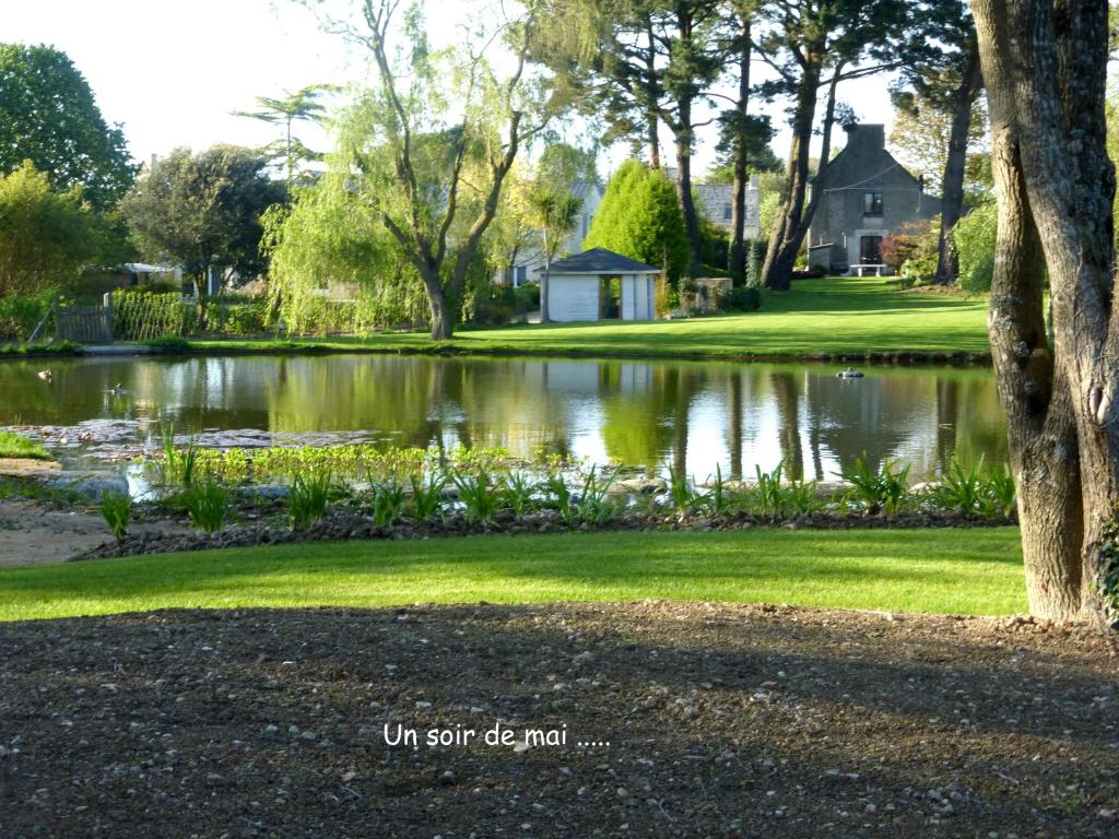 a pond in a yard with a house in the background at Domaine Paysager de Kertanguy in Garlan