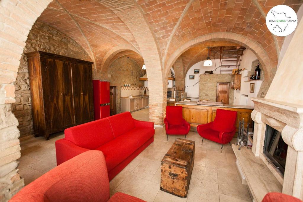 sala de estar con sofá rojo y sillas rojas en Casa Scuderia en Volterra