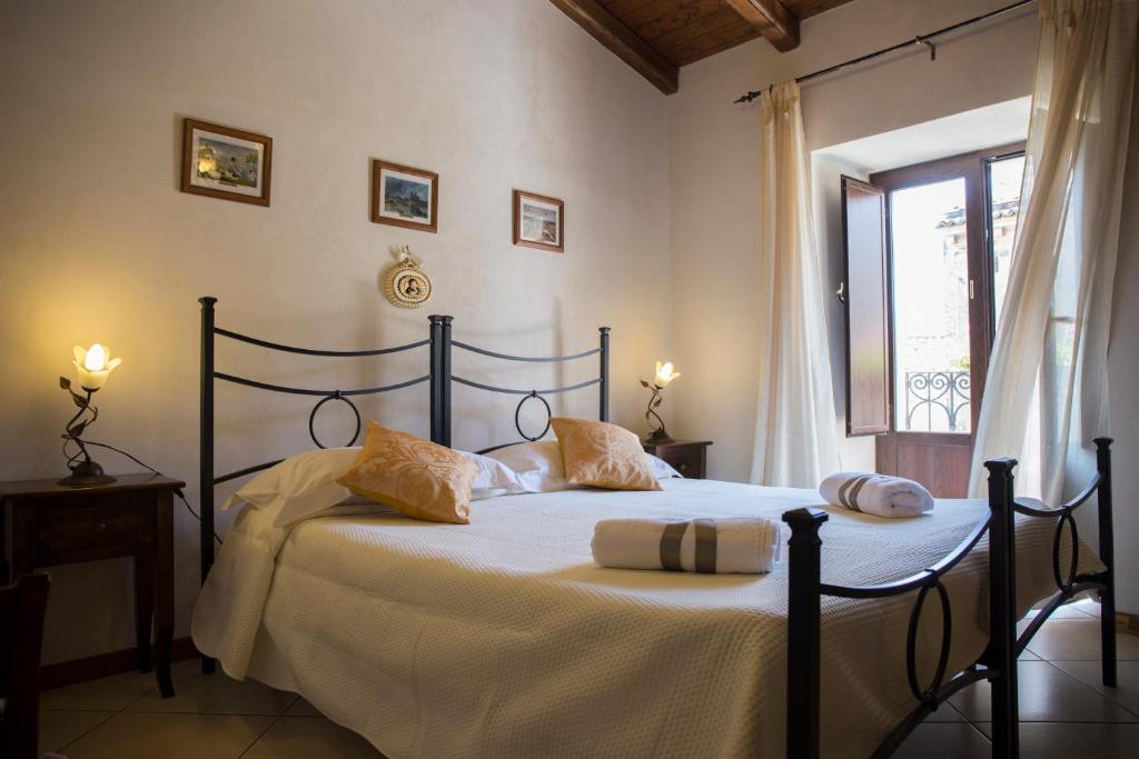 a bedroom with a bed with white sheets and a window at B&B Al Centro Storico in Nicolosi