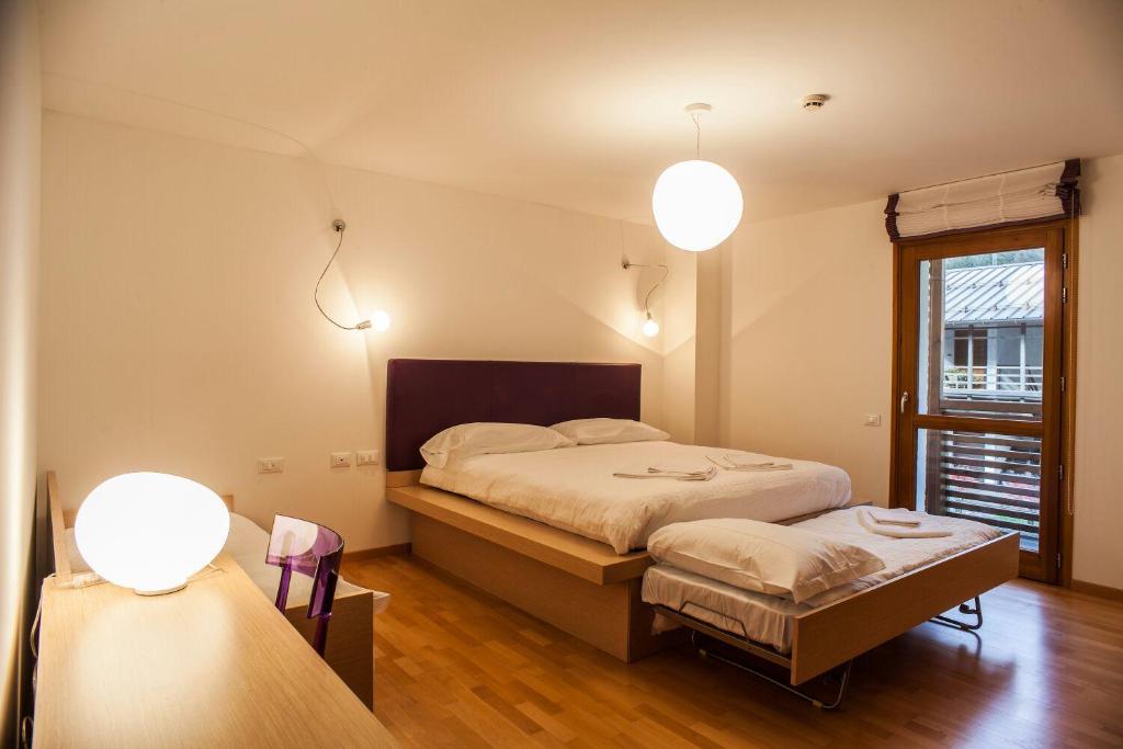 a bedroom with a bed and a window and two lights at Hotel Pramaggiore in Forni di Sotto