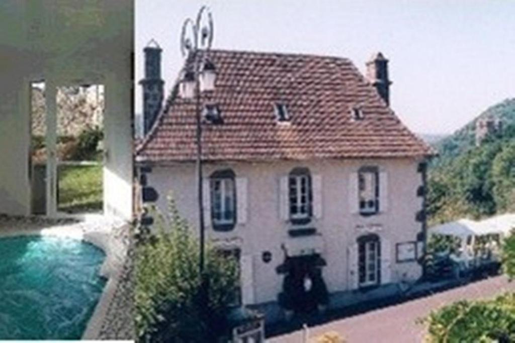 uma grande casa branca com uma piscina em frente em Auberge Hôtel de Tournemire - Cantal em Tournemire