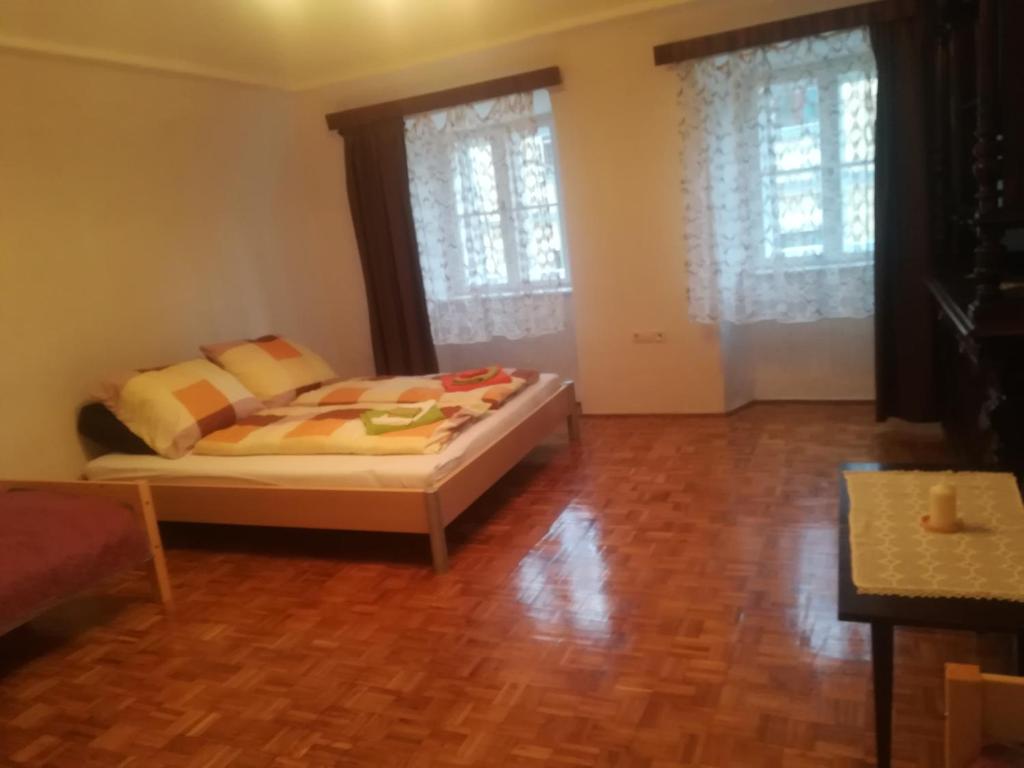 a bedroom with a bed and two windows at Apartman Bécsi utca in Sopron
