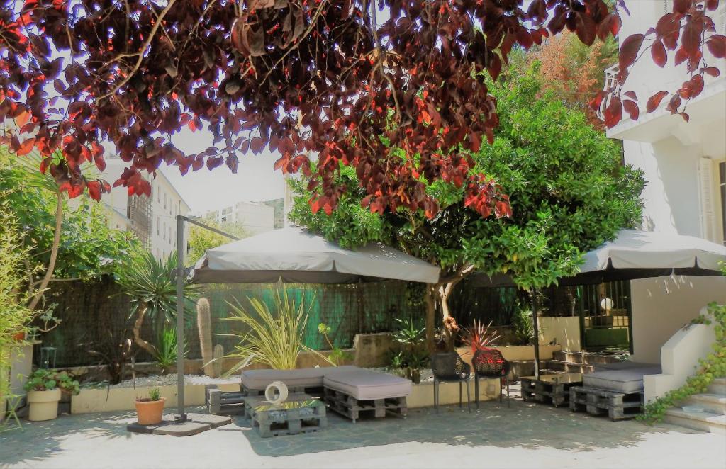 un patio con mesas, sombrillas y un árbol en Hotel Marengo en Ajaccio