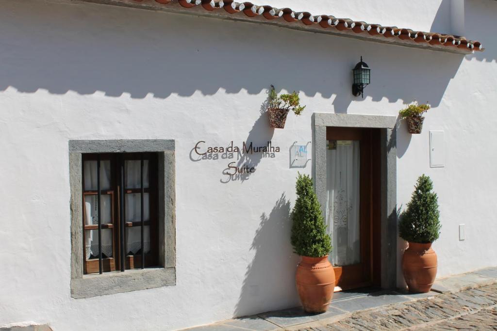 a white building with two potted plants next to a door at Casa da Muralha Suíte in Monsaraz
