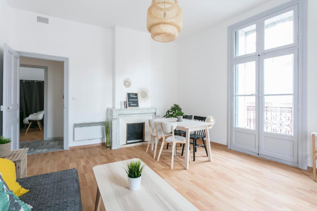 una sala de estar blanca con mesa y sillas en Flamingo appartement Diderot 2 Center, en Béziers