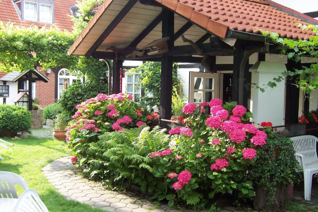 einen Garten mit rosa Blumen und einer hölzernen Pergola in der Unterkunft Hotel Café am Stift in Hessisch Oldendorf