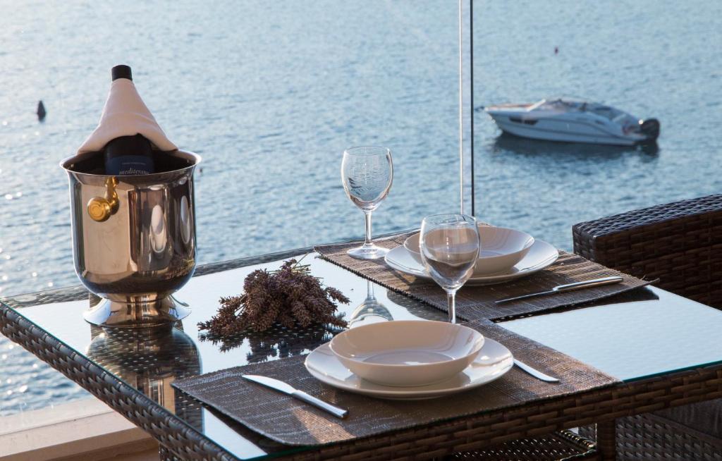 a table with plates and wine glasses and a view of the water at Apartments Lanterna in Rogoznica