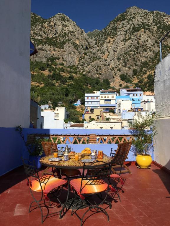 a table and chairs on a balcony with a mountain at Dar Dalia in Chefchaouen