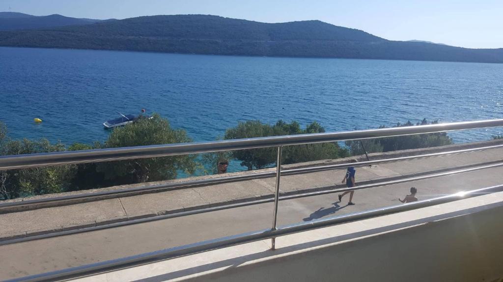 two people walking on a road next to a body of water at Apartman Ana in Neum