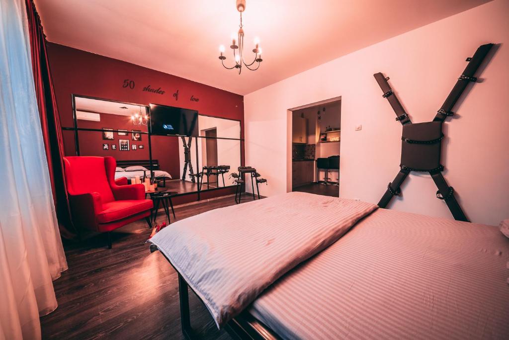 a bedroom with a bed and a red chair at 50 Shades of Love in Timişoara