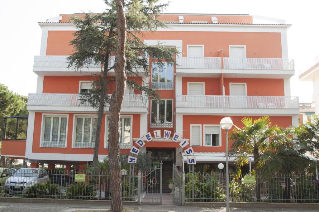 un edificio naranja con un árbol delante de él en Hotel Edelweiss, en Cervia