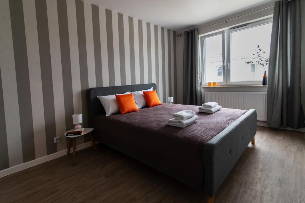 オルシュティンにあるBeżowe Loveのベッドルーム1室(オレンジ色の枕と窓付)