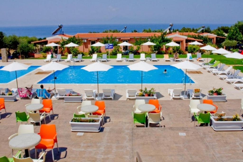 a group of chairs and tables and umbrellas next to a pool at Fournia Village in Kyllini