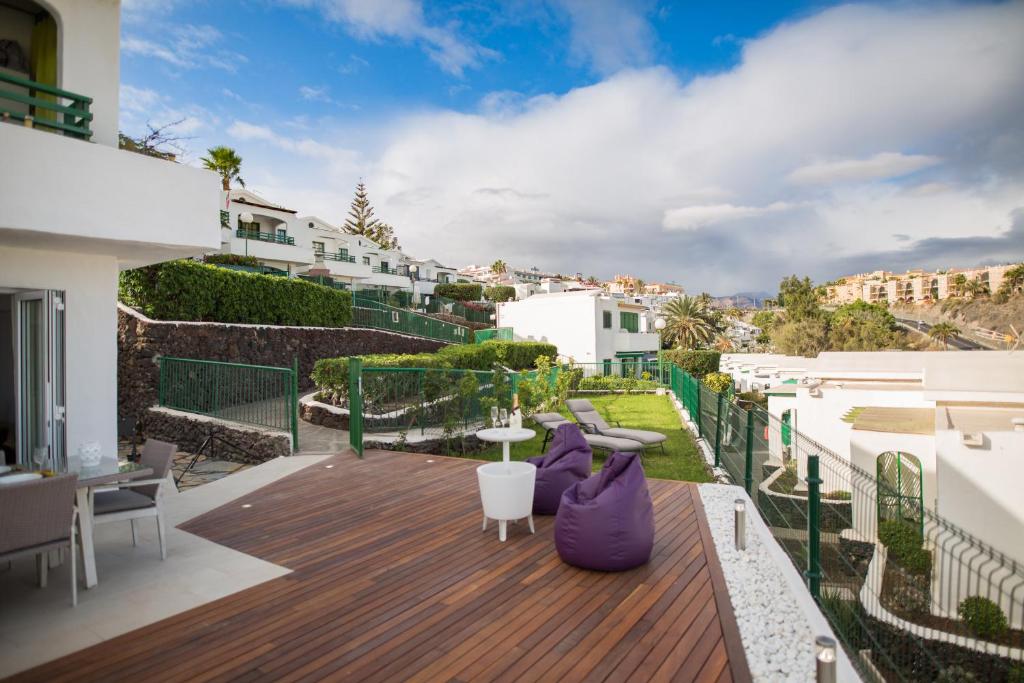 Un balcón con una terraza de madera con muebles morados. en Bungalow con vistas espectaculares, en Maspalomas