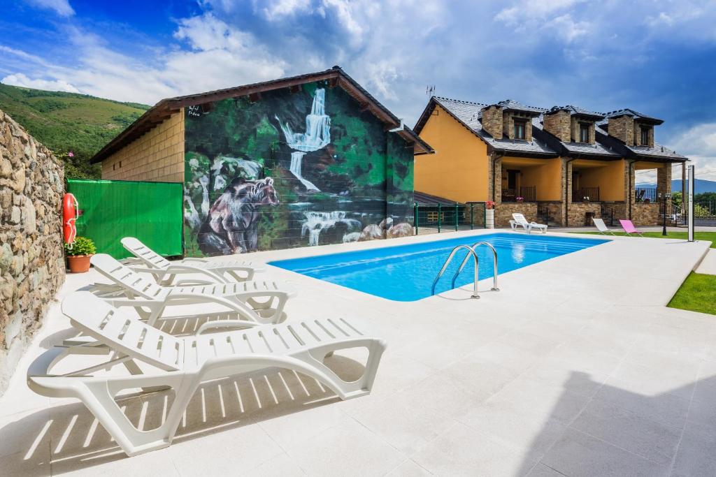 una piscina con 2 tumbonas y una casa en Apartamentos Rurales L´Abiseu en Caboalles de Abajo